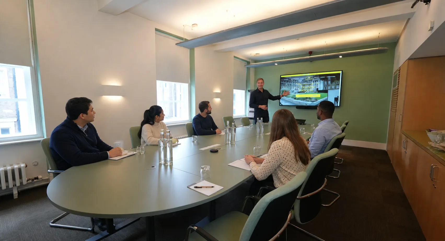 An SEO trainer presenting to five team members in a conference room